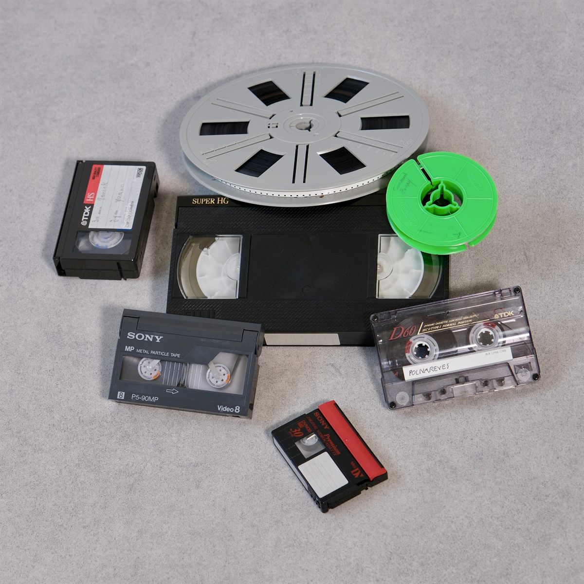 Cassettes VHS, Video8, MiniDV, une bobine de film Super 8 et une cassette audio, prêtes à être numérisées